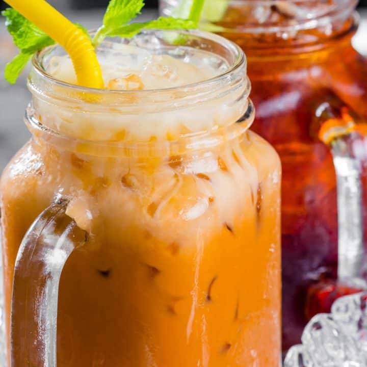 Thai iced tea in a mason jar with yellow straws.