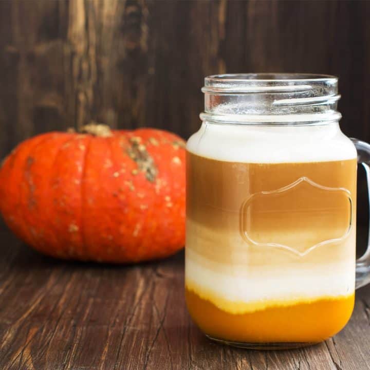 pumpkin spice chai latte with a miniature pumpkin on a wood background