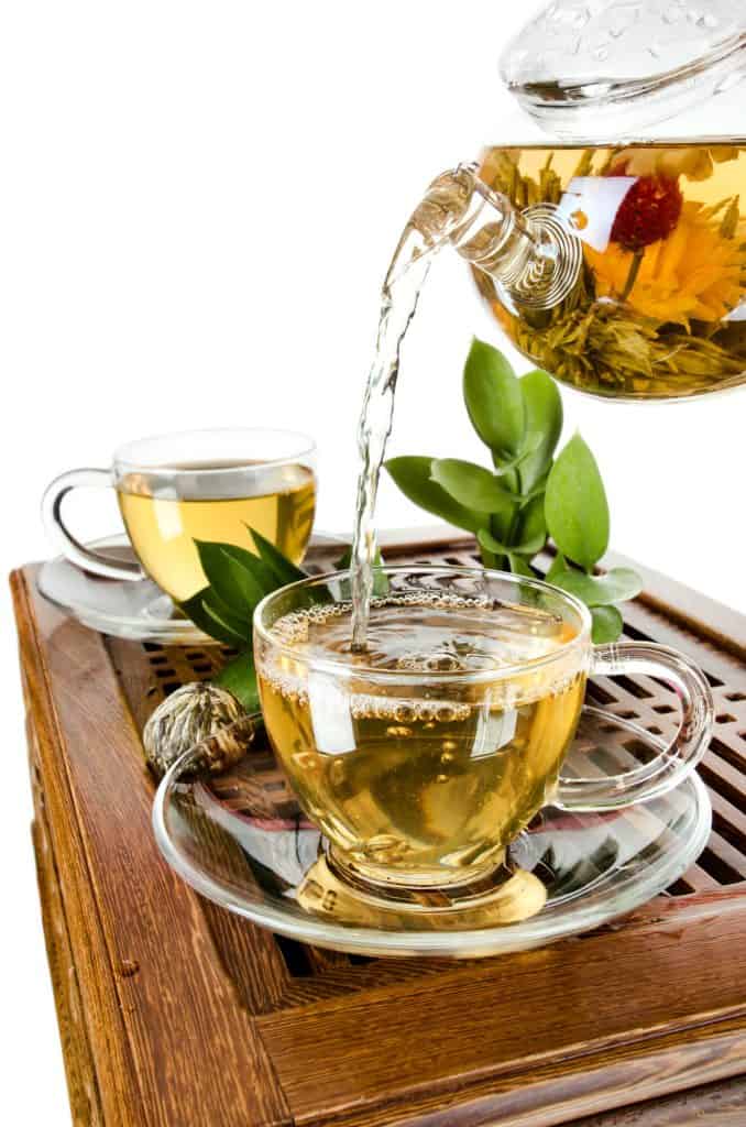 Glass teapot pouring tea into glass teacups
