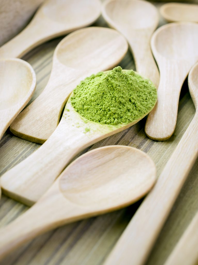 vibrant green matcha powder on a wooden spoon
