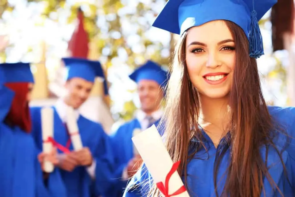 Girl graduate in blue cap and gown holding diploma. Graduation gifts daughter.